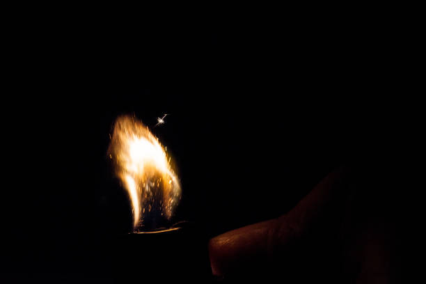 istock Close up view of real sparking light from lighter in dark black background 900849860