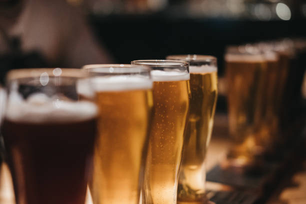 Close up of a rack of different kinds of beers, dark to light, on a table. stock photo