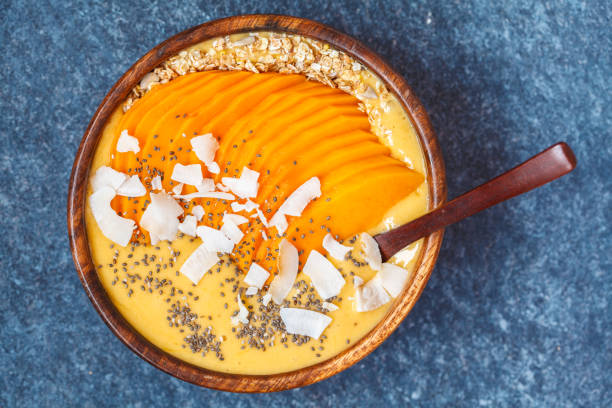istock Healthy breakfast mango smoothie bowl with chia seeds, mango slices, coconut slices and oat granola. Banana nice cream. Healthy vegan food concept. 900852356