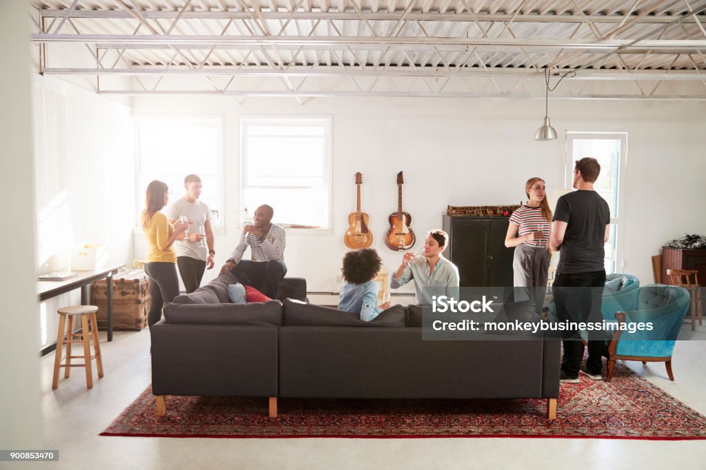 Friends at a party in a New York loft apartment, full length Party - Social Event Stock Photo