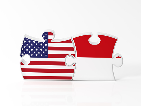 Jigsaw puzzle pieces textured with American and Indonesia flags on white. Horizontal composition with copy space. Clipping path is included.