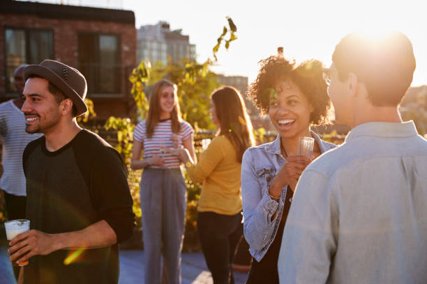 Happy friends at a rooftop party backlit by sunlight Happy friends at a rooftop party backlit by sunlight party social event stock pictures, royalty-free photos & images