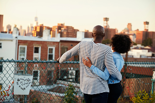 Young black couple embracing on Brooklyn rooftop, back view