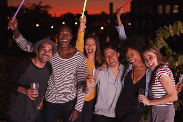 Happy friends waving glowsticks at rooftop party in Brooklyn Happy friends waving glowsticks at rooftop party in Brooklyn glow stick stock pictures, royalty-free photos & images