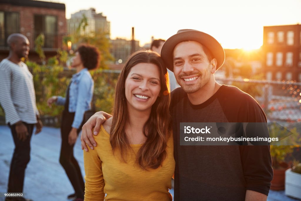 Young adult couple embracing at a rooftop party Couple - Relationship Stock Photo