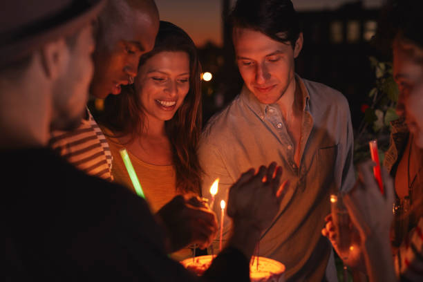 istock Friends on a rooftop lighting candles on a birthday cake 900855914