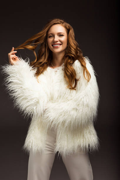 istock smiling girl in fluffy jacket touching hair isolated on gray 900856268