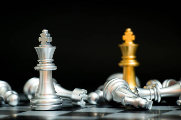 istock Gold king in chess game face with the another silver team on black background (Concept for company strategy, business victory or decision) 900857132