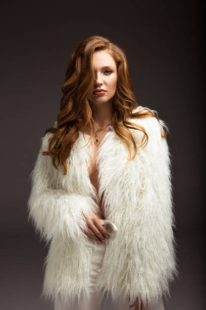 istock attractive brown-haired woman in fluffy jacket isolated on gray 900859844