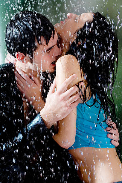 Young couple hugging and kissing under a rain stock photo