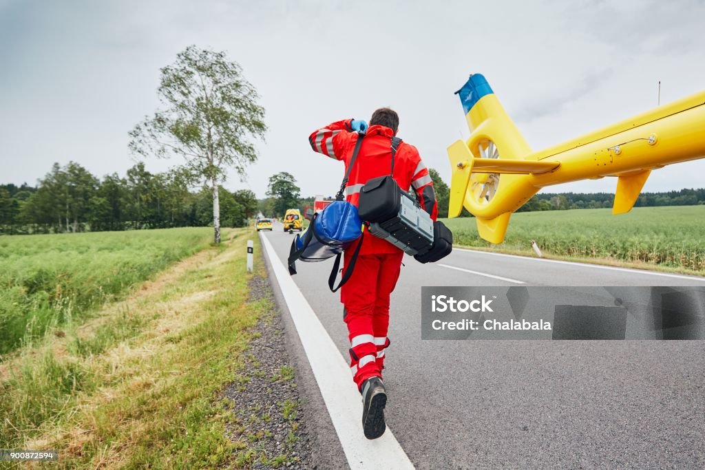 Helicopter emergency medical service Doctor with defibrillator and other equipment running from helicopter. Teams of the Emergency medical service are responding to an traffic accident. Paramedic Stock Photo