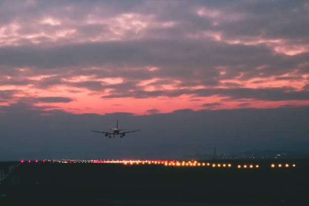 旅客又は貨物飛行機が赤い夕日の背景に滑走路に着陸します。 - airport runway airplane commercial airplane ストックフォトと画像