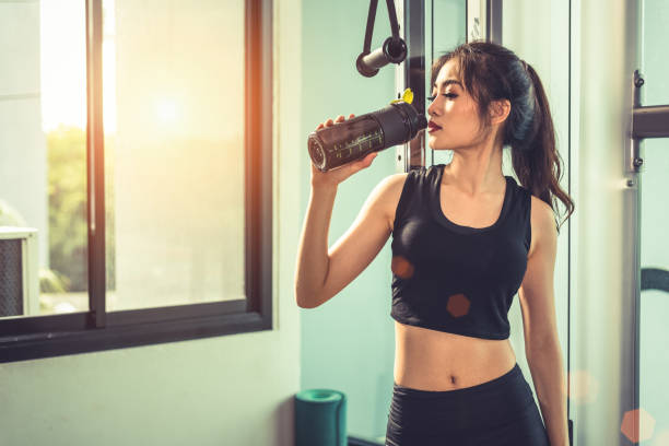 Asian young woman drinking protein shake or water after exercises at fitness gym. Strength training and muscular. Beauty and Healthy concept. Relax concept. Sport equipment and Club center theme. Asian young woman drinking protein shake or water after exercises at fitness gym. Strength training and muscular. Beauty and Healthy concept. Relax concept. Sport equipment and Club center theme. chest dip on athletic workout stock pictures, royalty-free photos & images