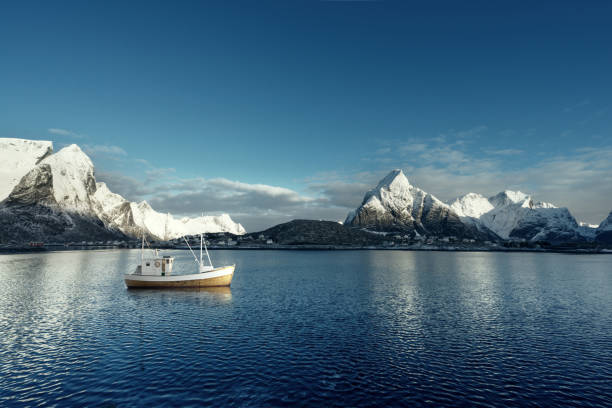 fischerboot und reine village, lofoten, norwegen - mountain peak norway reflection sunlight stock-fotos und bilder