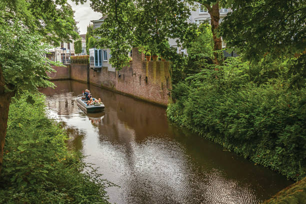 壁とスヘルトーヘンボスの豊かな植生に囲まれた運河を移動する人々 とボートします。 - wavelet �ストックフォトと画像