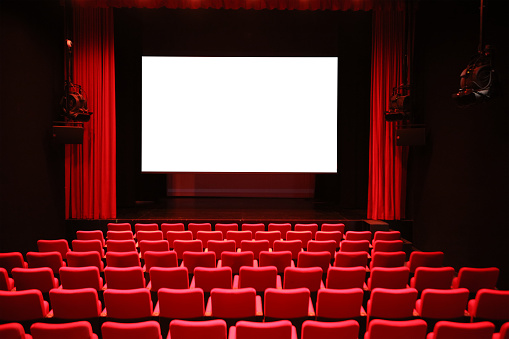 Empty cinema with white screen, red curtains drawn and rows of vacant seats from the rear. 3d rendering