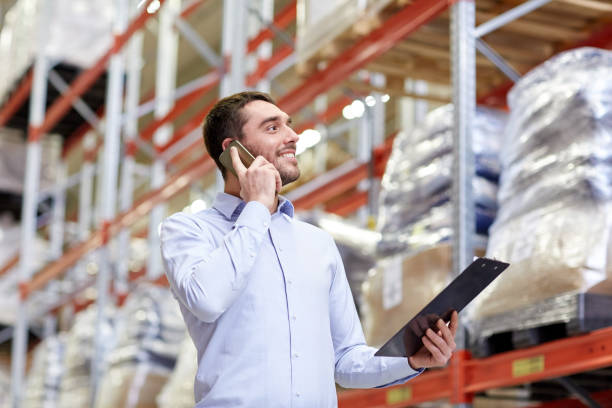 istock man with clipboard and smartphone at warehouse 900904046