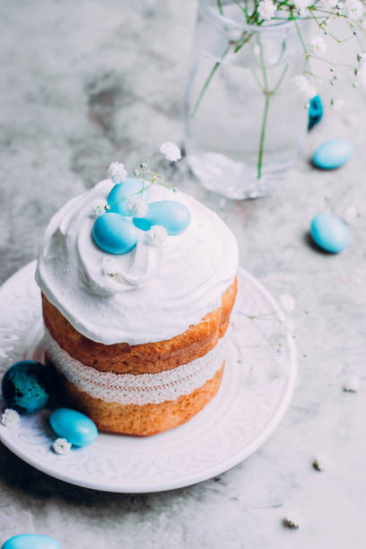 istock Easter cake kulich. Traditional Easter sweet bread decorated meringue and blue candy cane shape eggs on plate on gray stone table background. Copy space. 900905056
