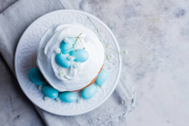 istock Easter cake kulich. Traditional Easter sweet bread decorated blue candy cane shape eggs on plate on gray stone table background. Copy space, top view 900905068