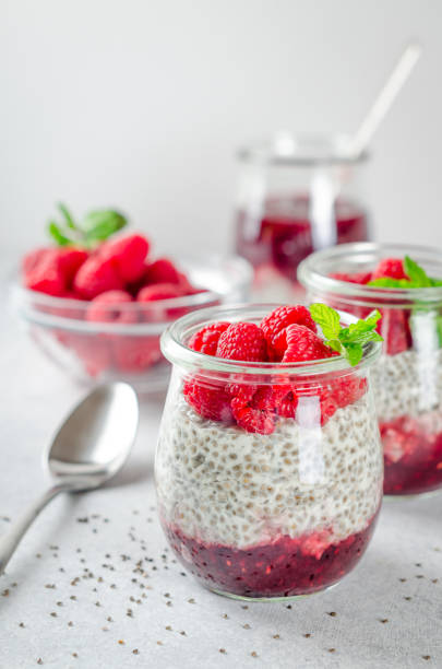 istock Two glass jars with chia pudding with raspberry and jam. Bowl of 900912798