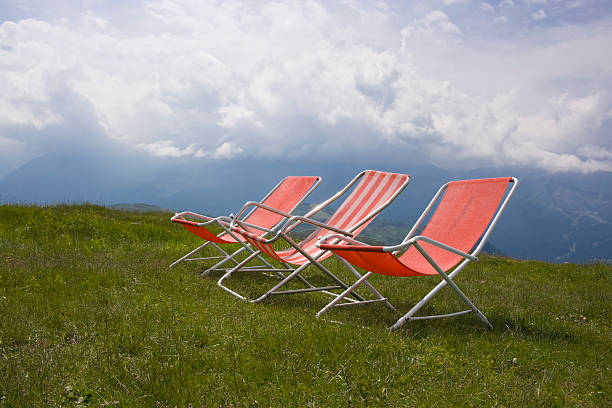 Folding chair surrounded by green leaves in a garden. Relaxation in the garden. Cottage aesthetics. Vacation outside the city. Warm summer day.