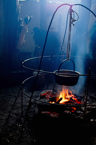 Large black cauldron suspended over an open fire.