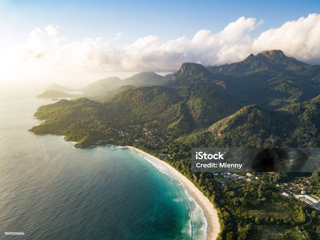 Grand Anse Mahe Island Seychelles Beach Coastline Overlooking the beautiful Grand Anse Beach, West Coast and surrounding hills and mountains on Mahé Island close to sunset. Grand Anse on Mahé is one of the island's longest beaches, and the longest stretch of sand on Mahé's western coast. Grande Anse, Mahe Island, Seychelles Islands, Africa Aerial View Stock Photo