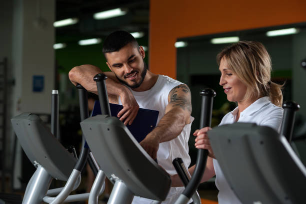 istock Middle aged woman working out in gym with coach 900941896