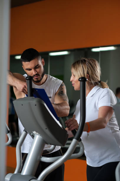 istock Middle aged woman working out with coach in gym 900942044