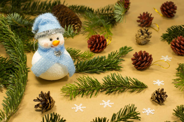 istock Snowman among fir branches and cones. Yellow background 900942254