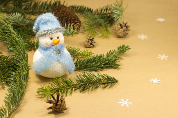 istock Snowman among fir branches and cones. Yellow background 900945420