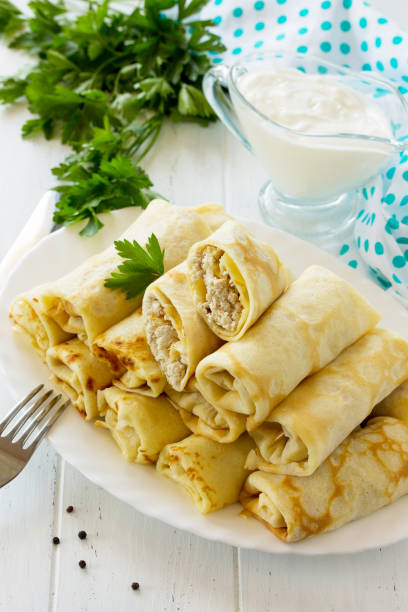 istock Pancake breakfast. Pancakes with meat stuffing, served with sour cream sauce on the kitchen wooden table. 900946272