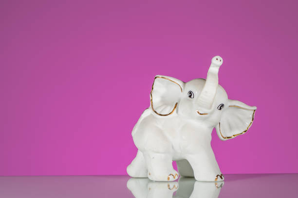 Closeup of white elephant made of porcelain Closeup of white elephant made of porcelain, pink background elephant figurine stock pictures, royalty-free photos & images