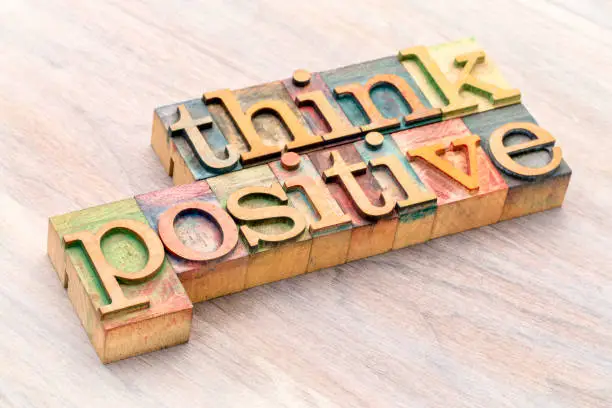 Think positive - word abstract in vintage letterpress wood type blocks against grained wooden background