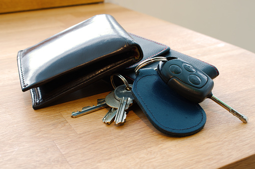 Wallet, car key, house keys and mobile phone on a table together in such a way that looks like someone is about to leave or has just arrived. Photographed; Barnstaple, Devon, UK. December 2017