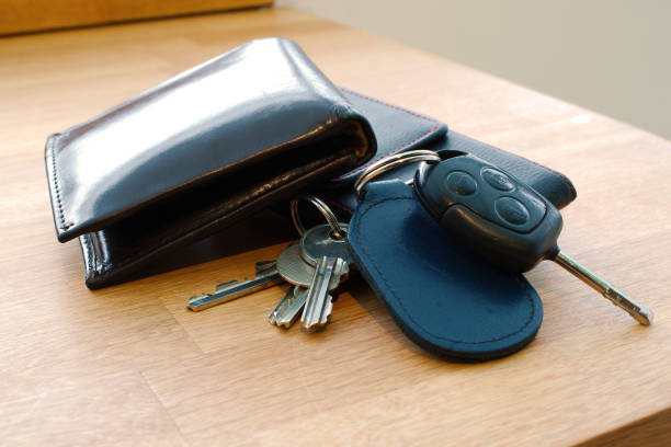 Wallet, car key, house keys and mobile phone on a table. Wallet, car key, house keys and mobile phone on a table together in such a way that looks like someone is about to leave or has just arrived. Photographed; Barnstaple, Devon, UK. December 2017 car keys table stock pictures, royalty-free photos & images
