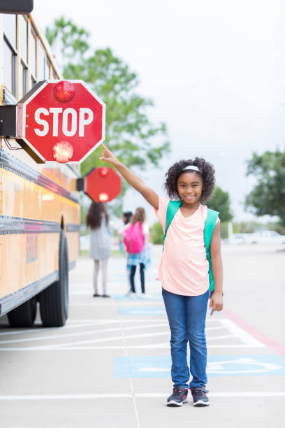 istock Schoolgirl points to stop sign on school bus 900966086