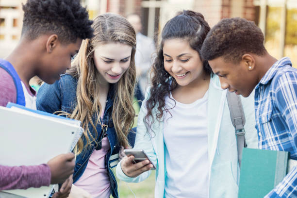 istock Diverse group of high school students looking at something on smart phone together 900966274