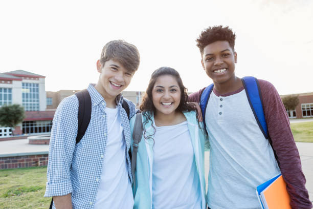 istock Diverse high school students smiling at camera with arms around each other 900966294