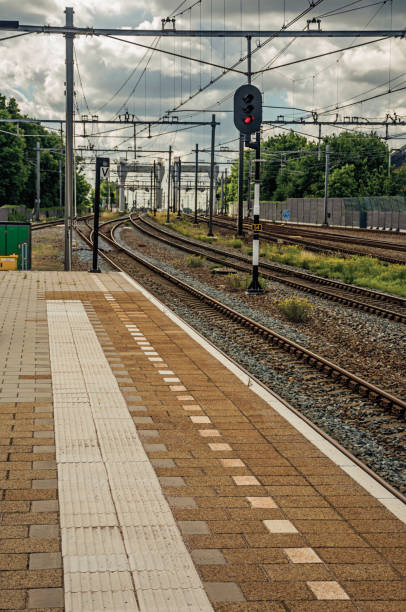 istock Platform, railroad rails and signaling at train station under blue cloudy sky at Weesp. 900972930