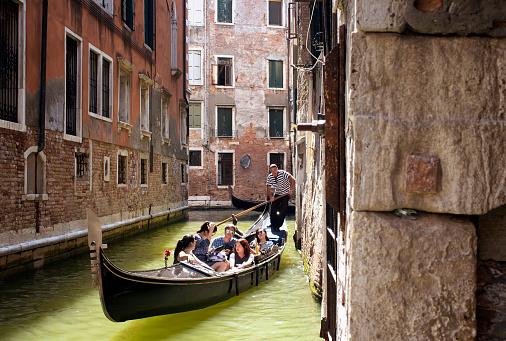 Asian tourist family rides a gondola tour on canals in Venice / Italy.