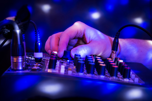 DJ mixing party music on blue background with lights.