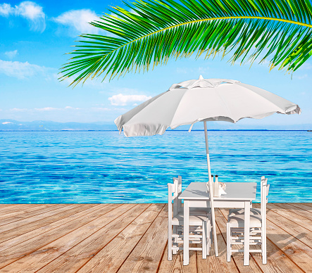 Blue sea, palm tree leaf and wooden chair with chair on wooden terrace