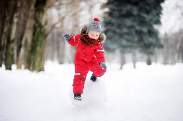 istock Little boy in red winter clothes having fun with snowball 901001340