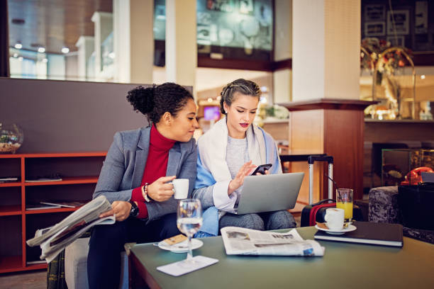 mujeres en viaje de negocios son mensajes de texto y a la espera para el check-in - hotel newspaper coffee reading fotografías e imágenes de stock