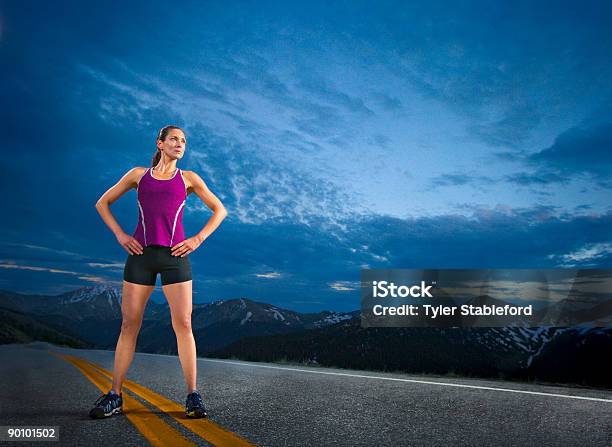 A Female Runner Stands Confidently On A Road Stock Photo - Download Image Now - Front View, Hand On Hip, Mountain