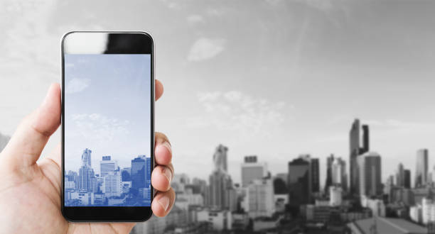 istock Hand holding mobile smart phone, black and white city background 901034232