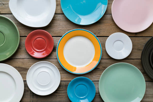 Empty color plates and utensil on wooden table background, top view with copy space