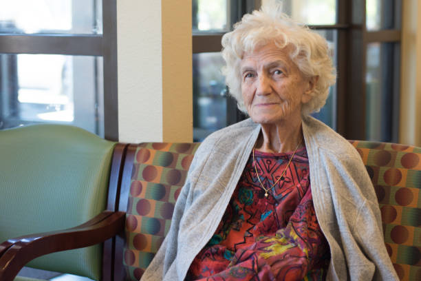 Elderly woman sitting in a waiting room at doctor or counselor's office, USA.