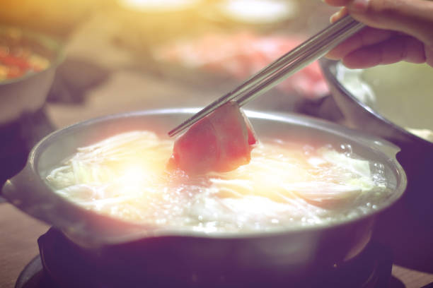 しゃぶしゃぶしゃぶ鍋、熱湯でゆで肉で箸を持っている手 - shabushabu ストックフォトと画像